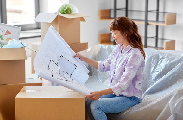 mujer con plano y cajas que se mudan a un nuevo hogar - Foto, Imagen