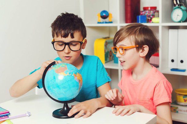 School kids studying a globe. Education and geography. Back to school. Smiling students looking at globe. Smart boys studying geography. Kids doing homework together. - Photo, Image