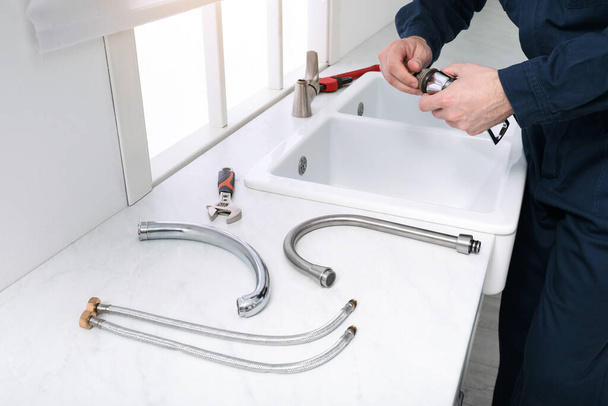 Professional plumber fixing water tap in kitchen, closeup - Photo, image
