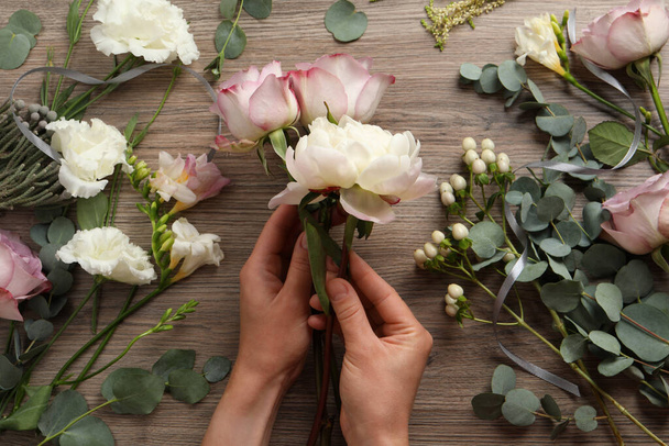 Florist creating beautiful bouquet at wooden table, top view - Φωτογραφία, εικόνα