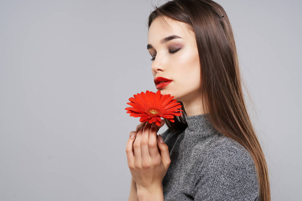 mooie brunette met rode bloem heldere make-up model - Foto, afbeelding