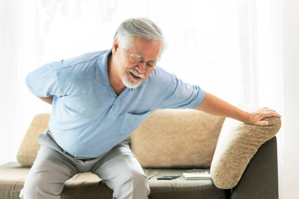 ソファで高齢者,腰痛に苦しむアジアの高齢者 – 医学と医療の概念 - 写真・画像