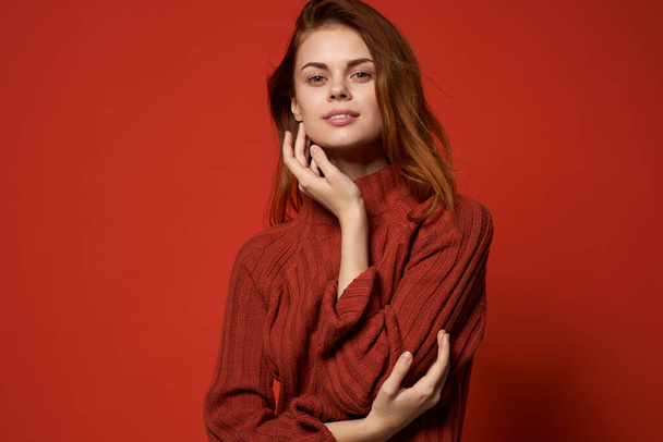 vrouw in rode trui levensstijl glamour cosmetica rode achtergrond - Foto, afbeelding