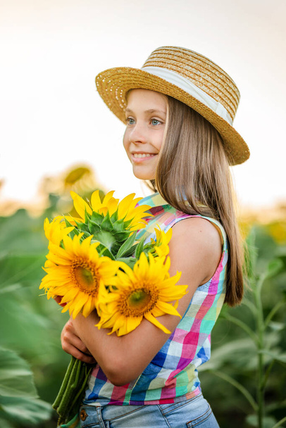 A beautiful happy little girl  in a field of sunflowers. Summer cozy mood. - Photo, Image
