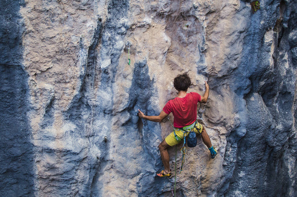 Ένας δυνατός άντρας σκαρφαλώνει σε βράχο, δυνατοί μύες της πλάτης, αναρρίχηση στην Τουρκία, αντοχή στην προπόνηση και δύναμη, άνθρωπος σε extreme sport, ορειβάτης προπονείται στη φύση. - Φωτογραφία, εικόνα