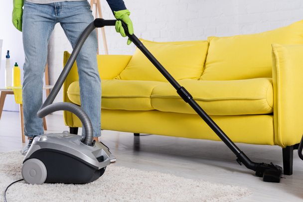 Cropped view of man vacuuming floor near couch  - Photo, Image