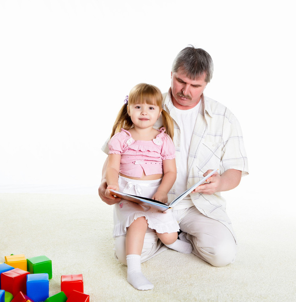 Grandfather and his little granddaughter together reading a book - Фото, изображение