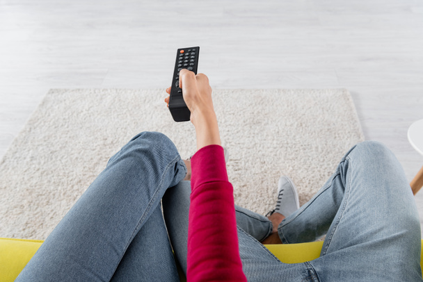 Cropped view of woman clicking channels near boyfriend on couch  - Фото, зображення