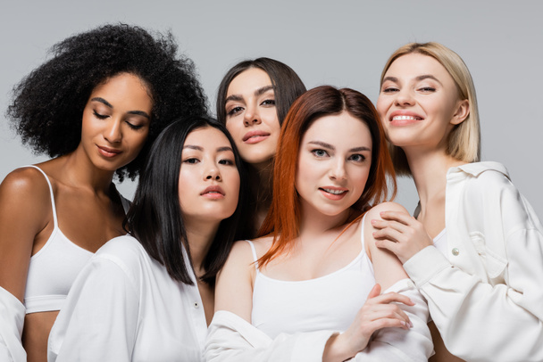 asian and african american models in white shirts posing with cheerful women isolated on grey - Foto, Bild