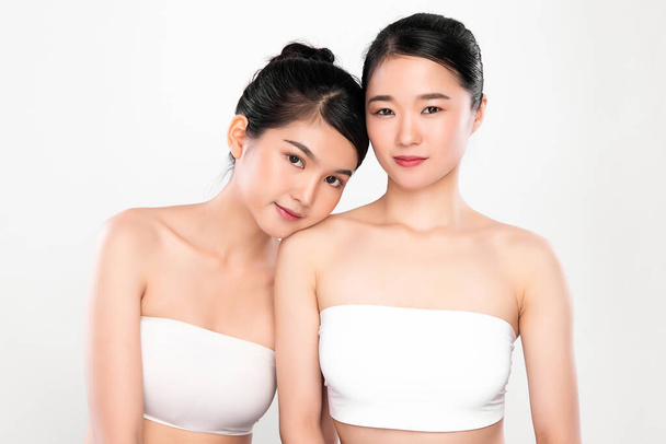 Две красивые молодые азиатские женщины с чистой свежей кожей на белом фоне, уход за лицом, уход за лицом, косметология, красота и спа, портрет азиатских женщин. - Фото, изображение