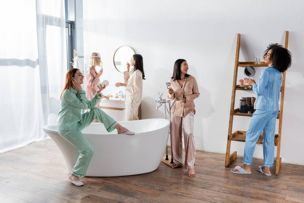 szczęśliwy międzyrasowe kobiety w oczy przepaski uśmiechając się w łazienka podczas piżama party  - Zdjęcie, obraz