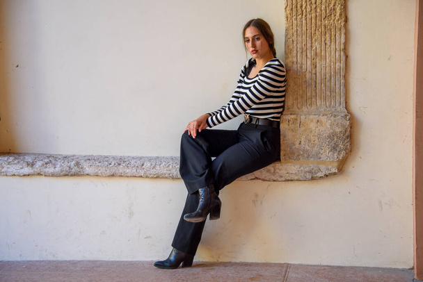 Молодая красивая стильная девушка, с черно-белым полосатым свитером и черными брюками, прогулки по городу. - Фото, изображение