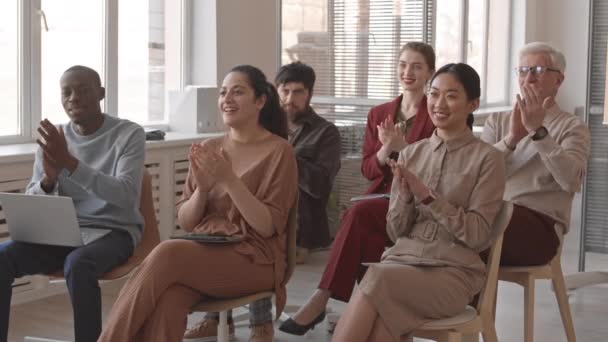 Medio largo de jóvenes y mayores, mujeres y hombres de negocios multiétnicos sentados en sillas, aplaudiendo a intérprete invisible, con formación - Metraje, vídeo