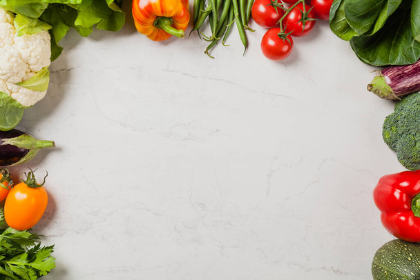 Stone background with a border of fresh vegetables.  Top view. - Foto, afbeelding