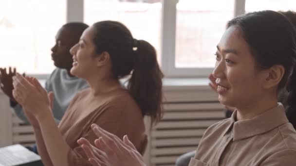 Primo piano medio di giovani e anziani, donne e uomini multietnici seduti in ufficio che applaudono a performer invisibili, in formazione aziendale - Filmati, video