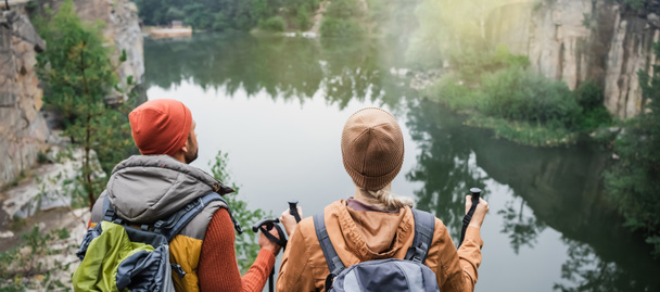 visão traseira do casal com mochilas perto do lago na floresta, banner - Foto, Imagem