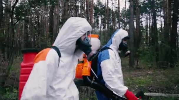 Эпидемиологи в защитных костюмах прогуливаются по лесу - Кадры, видео
