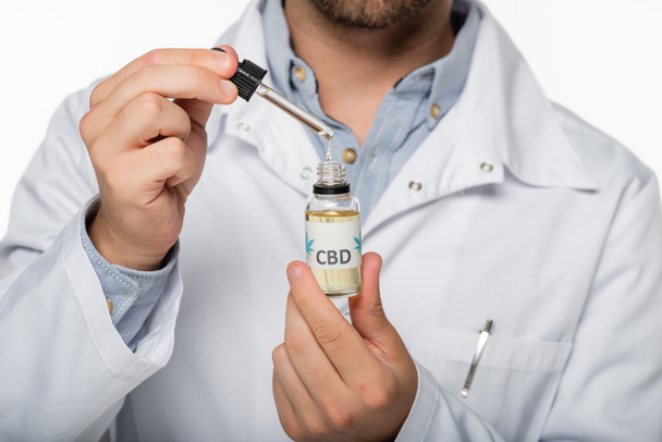 Teilansicht des Arztes mit Fläschchen mit Cannabisöl auf weiß isoliert - Foto, Bild