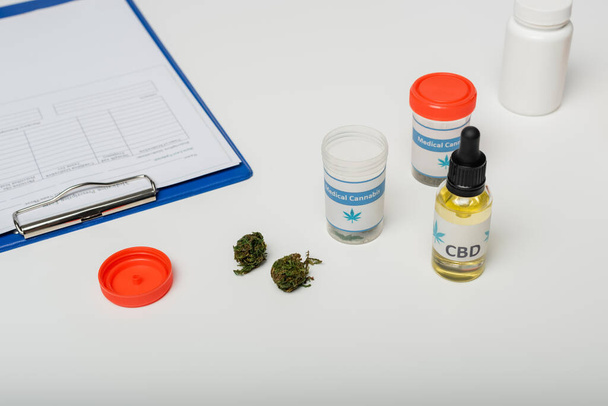 orvosi kannabiszból készült gyógyszeres tartályok a vágólap közelében, fehér íróasztalra felírt recepttel - Fotó, kép