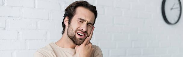 Muž dotýká tvář, zatímco trpí bolestí zubů, prapor  - Fotografie, Obrázek