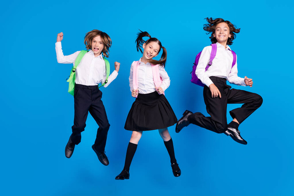 Photo of crazy relaxed kids jump boy celebrate victory wear rucksack uniform shoes isolated blue color background - Fotoğraf, Görsel