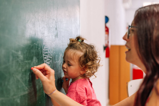Νηπιαγωγείο δάσκαλος υποστηρίζει το παιδί στην τάξη - Φωτογραφία, εικόνα