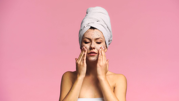woman with naked shoulders and towel on head applying face mask isolated on pink - Foto, afbeelding