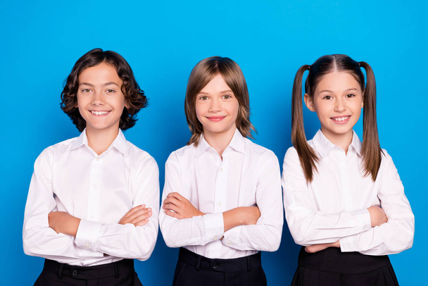 Photo of cheerful confident schoolkids crossed hands wear school uniform isolated blue color background - Foto, afbeelding