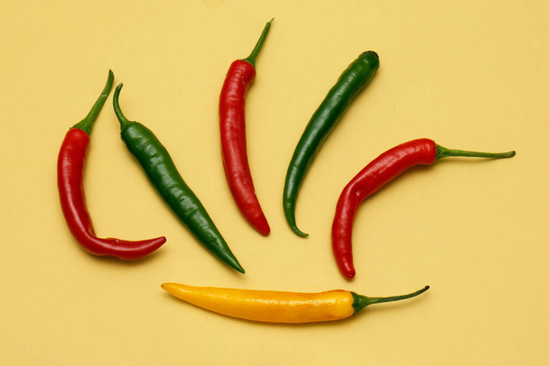 Colorful spicy chilli and habanero hot peppers on yellow background - Fotoğraf, Görsel