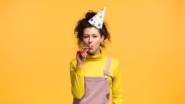 cheerful woman in yellow turtleneck blowing in party horn isolated on orange - Photo, Image