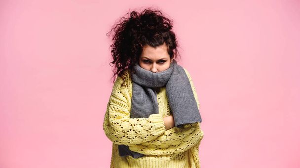 frozen woman in warm scarf and knitted sweater standing with crossed arms isolated on pink - Foto, Imagem
