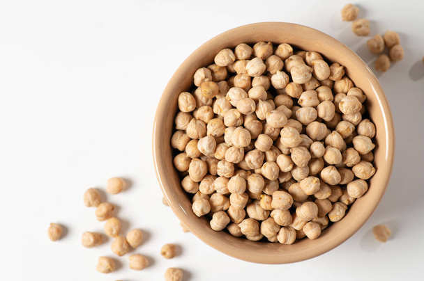 dry chickpeas, in a ceramic dish on a white table, top view, close-up - Foto, afbeelding