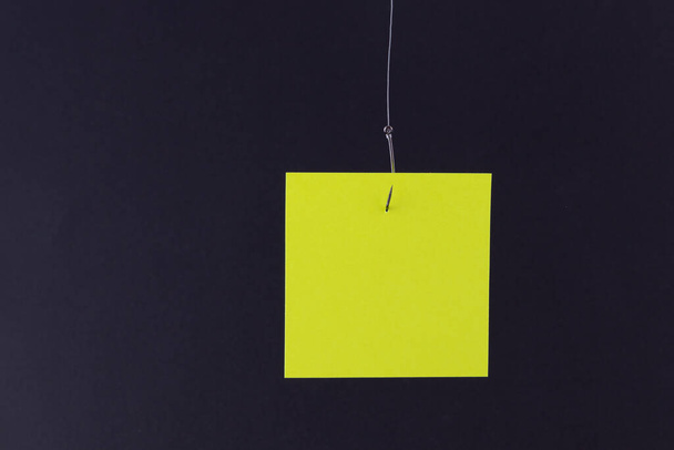 Mockup of a Blank Yellow Memo Paper with Copy Space Hanging on a Fishing Hook - Foto, imagen