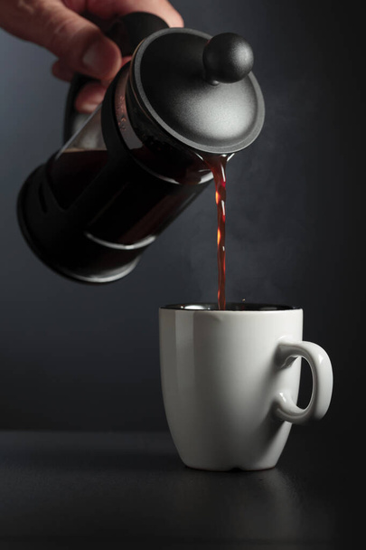 Verter café francés en una taza sobre una mesa negra. - Foto, Imagen