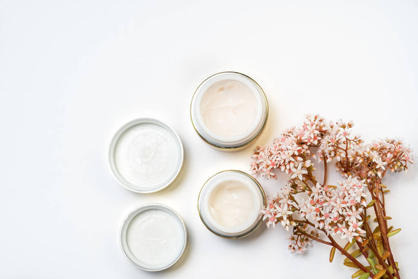cosmetics for the face. eye cream and a bunch of pink flowers on a white background - Valokuva, kuva