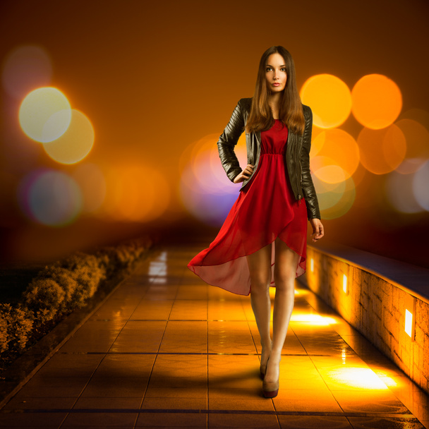Mujer vestida de rojo caminando por la ciudad nocturna
 - Foto, imagen