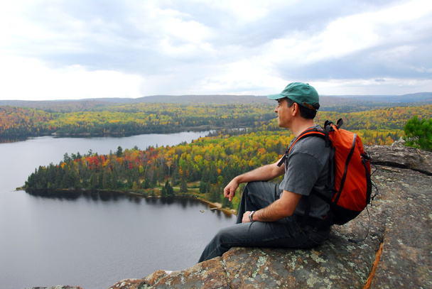 A hiker sitting on a cliff edge enjoying scenic view - Photo, Image