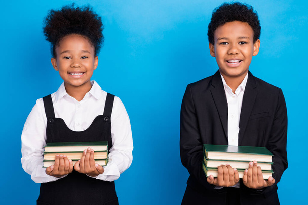 Photo of happy positive dark skin children pupils hold materials books smile isolated on blue color background - Fotografie, Obrázek