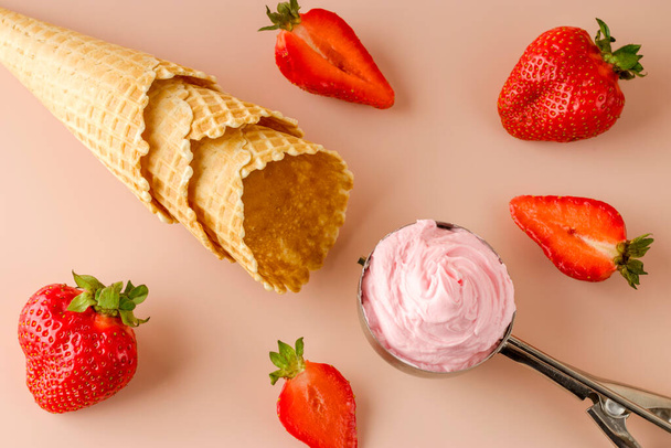Luonnollinen mansikka jäätelöä erityinen lusikka. Tuoreita mansikoita ja vohvelikeksejä vaaleanpunaisella pohjalla. Kylmä kesäjälkiruoka. Litteä. - Valokuva, kuva
