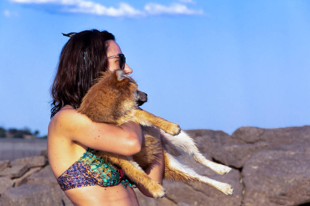 Jeune femme avec son chien poméranien dans ses bras dans la nature. - Photo, image
