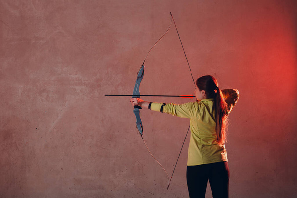 Archer woman with modern block sport bow and arrow indoor - Photo, Image