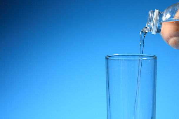 Limpia el agua potable en un vaso sobre un fondo azul. concepto de agua potable saludable - Foto, imagen