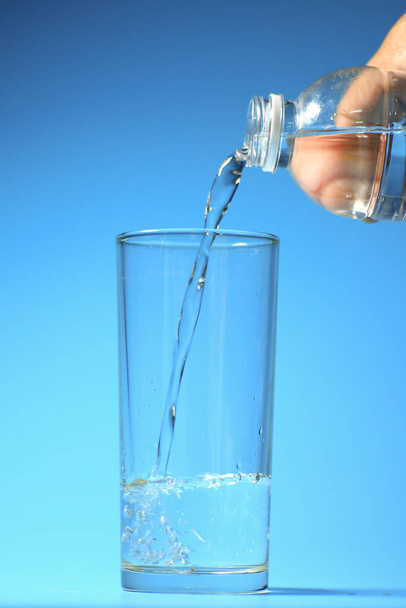 Schoon drinkwater in een glas op een blauwe achtergrond. gezond drinkwaterconcept - Foto, afbeelding