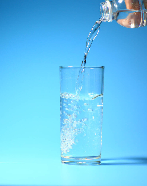 Καθαρό πόσιμο νερό σε ένα ποτήρι σε μπλε φόντο. υγιεινό πόσιμο νερό έννοια - Φωτογραφία, εικόνα