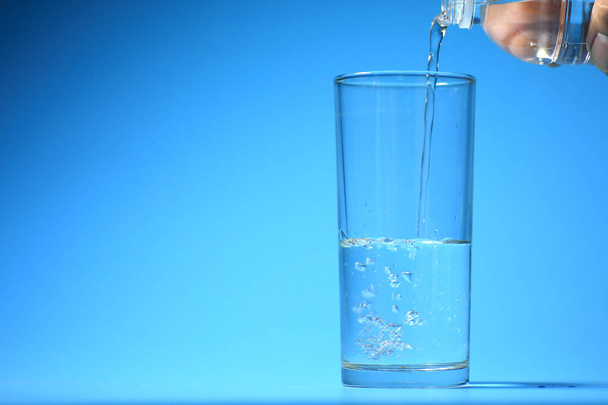 Чистая питьевая вода в стакане на синем фоне. концепция здоровой питьевой воды - Фото, изображение