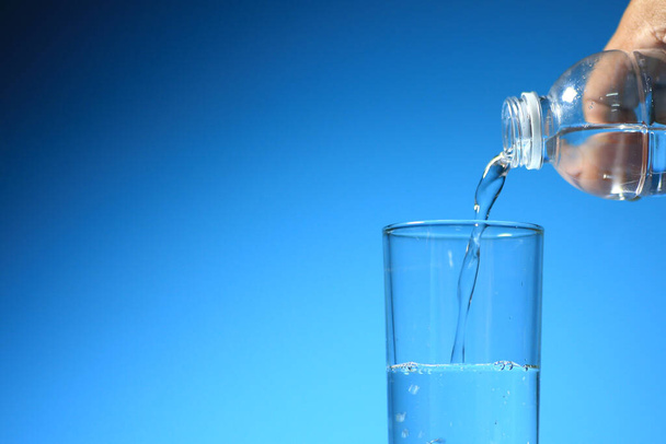 Clean drinking water in a glass on a blue background. healthy drinking water concept - 写真・画像