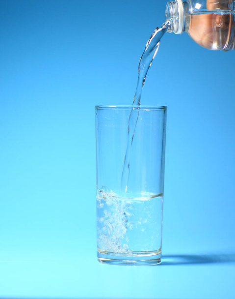 Καθαρό πόσιμο νερό σε ένα ποτήρι σε μπλε φόντο. υγιεινό πόσιμο νερό έννοια - Φωτογραφία, εικόνα