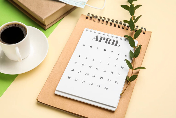 Calendar with cup of coffee and notebook on color background - Photo, Image