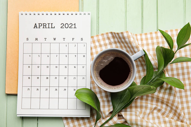 Calendario con tazza di caffè e taccuino su sfondo di legno a colori - Foto, immagini