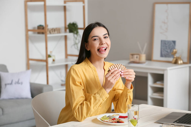 Красивая молодая женщина ест вкусную кесадилью дома - Фото, изображение